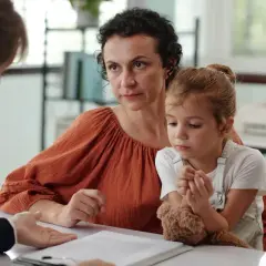 Matka z córką i terapeutką przy biurku, rozmowa o diagnozie.